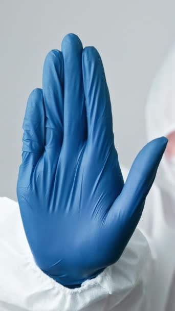 垂直ビデオ 病気を止めなさい 感染防止 ウイルス学者の医者だ 女性の医療専門家のパイプスーツ警告手青手袋ジェスチャーグレーの背景に隔離 — ストック動画