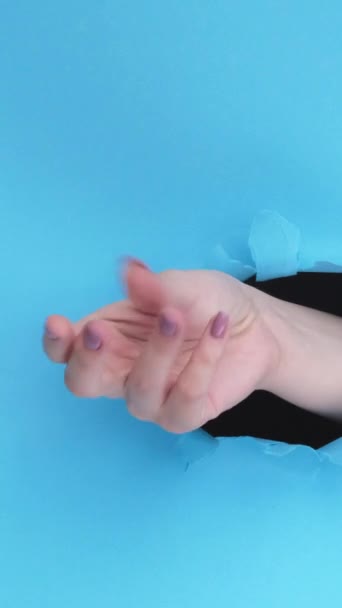 垂直录像 手指爆裂 容易的手势 蓝色撕破纸墙底座空隙环上的女性手突破孔 — 图库视频影像