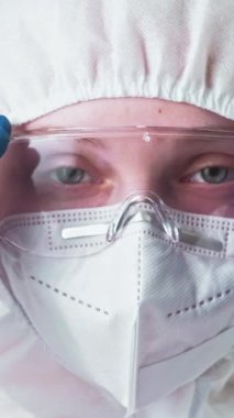 Dikey video. Laboratuvar uzmanı. Covid-19 koruması. Coronavirüs salgını. Kadın sağlık doktoru tıbbi koruma ekipmanı takıyor..