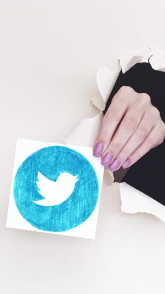 ハリコフ ウクライナ 2020年6月4日 垂直ビデオ Twitterロゴ ネットワークアプリ 女性加入者手で引き裂かれた画期的な紙穴ショーサイトアイコン上の白い背景ループ — ストック動画