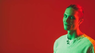Neon portresi. İnsanların reklamını yapmak. Yeşil ışık gülümseyen yakışıklı adam yüzü parlak kırmızı boşluk arka planında izole edilmiş..