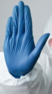 Dikey video. Virüsü durdur. Uyarı işareti. Bulaşıcı hastalık. Tıbbi doktor kadın uzman. Gri arka planda tehlike işareti olan mavi eldivenler..