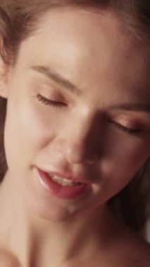 Dikey video. Cilt bakımı. Güzellik modeli. Kozmetik bakım. Muhteşem, mutlu, kendine güvenen genç bir kadın. Taze, ışıl ışıl bir yüzü var..