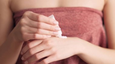 Eller cilt bakımı. Tedavi kozmetik. Besleyici ürün. Sabah rutini. Havluya sarılmış kadın duş aldıktan sonra cildine nemlendirici krem sürüyor..