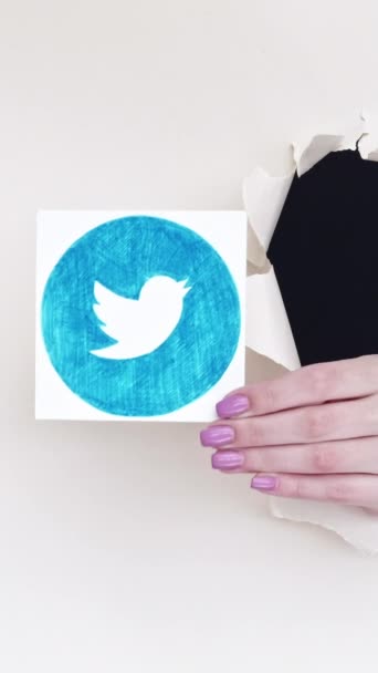 ハリコフ ウクライナ 2020年6月7日 垂直ビデオ Twitterアイコンについて ソーシャルメディア 女性のブロガーは白い空のスペースの背景にアプリのロゴを示す画期的な紙の穴の中を手渡します — ストック動画