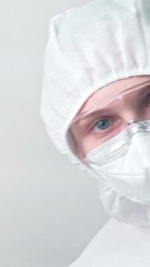 Dikey video. Hastane çalışanı. Agresif doktor. Virüsle savaş. Tıbbi uzman kadın, gri arka planda izole edilmiş titreyen yumruğu tehdit ederek uyarıyor..