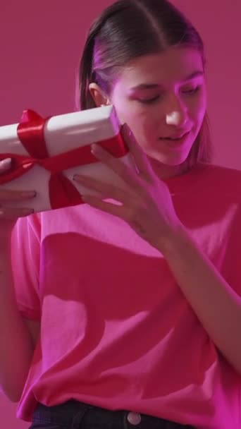 垂直录像 生日礼物 假日礼物 节日惊喜 快乐快乐的女人 带着包裹的盒子 背景是淡淡的淡红色 — 图库视频影像