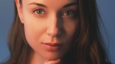 Cilt sağlığı. Yüz gerdirme prosedürü. Doğal güzellik bakımı. Çekici, sakin, pürüzsüz, parlak tenli, gri arka planda çıplak makyajlı bir kadın..