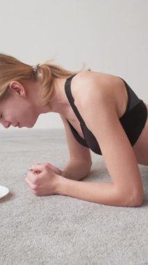 Dikey video. Yorucu bir diyet. Spor motivasyonu. Kilo verme eğitimi. Yorgun bir kadın elinde kalasla tatlı bir çörekle yerde sürünüyor..