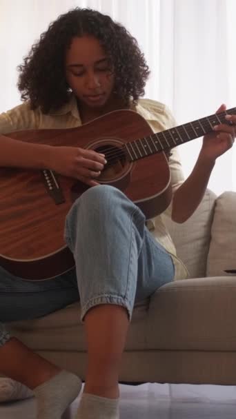 バーティカルビデオ ギターパフォーマー ミュージシャンライフスタイル ソング練習 自宅の部屋で音響弦楽器でメロディーを演奏する才能ある女性 — ストック動画