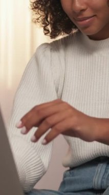 Dikey video. İnternet sörfü. Çevrimiçi boş zaman. Bilgisayarlı yaşam tarzı. Diz üstü bilgisayarda sohbet eden mutlu bir kadın evde ağ iletişiminin keyfini çıkarıyor..