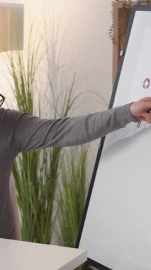 Dikey video. İstatistik sunumu. Veri analizi. İş görüşmesi. Ofis işyerindeki dizüstü bilgisayardaki toplantılarda haritaları açıklayan finansal grafikler sunan adam..