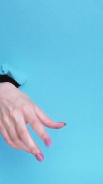 Kharkiv, Ukrayna - Haziran 04, 2020: Dikey video. Facebook ikonu. Kırık mavi arkaplan üzerinde mobil uygulama logosu kabul eden kadın abonenin eli kağıt deliğinin içinde.