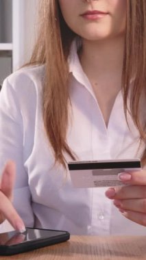 Dikey video. Mobil bankacılık. Çevrimiçi işlem. Tanımlanamayan iş kadını elleri ve kredi kartı nakitsiz internet alım-satımı için telefon başvurusunda yazıyor..
