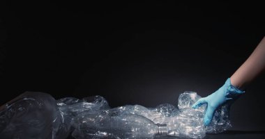 Atık toplama. Çöp geri dönüşümü. Plastik küçültme. Gönüllü eller eldivenlere. Kullanılmış şişeleri topluyorlar. Çöp kutusundan..