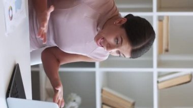 Dikey video. Kızgın patron. İş çatışması. İnternet iş görüşmesi. Sinirli iş kadını dizüstü bilgisayara bağırıyor ofisteki kağıtları fırlatıyor..