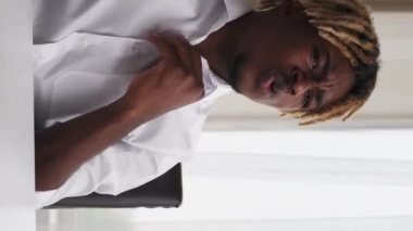 Dikey video. Güzel ofis. Kırık ısı sistemi. Yorgun bir iş adamı. Kaynama gününden muzdarip. Masada oturup iş yerindeki belgelerle rüzgar savuruyor..