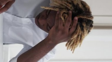 Dikey video. İş yorgunluğu. Yorgun bir çalışan. Hafif ofisteki aşırı yükleme yüzünden baş ağrısı çeken bıkkın iş adamı..