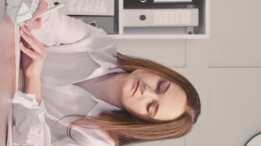 Dikey video. Fikir üretmek. Ofis yazısı. Belgelerle çalışan konsantre iş kadını buruşuk kağıtları atmaktan zevk alıyor..