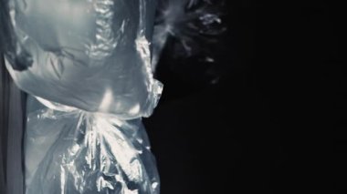 Dikey video. Plastik kirliliği. Tekrar kullanım israfı. Ekoloji problemi. Şişirilmiş şeffaf selofan poşetler yığının içine saçılmış, kara arka planda izole bir şekilde uçuyor..