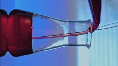 Dikey video. Kimyasal test. Eczacılık gelişimi. Laboratuvar araştırması. Cam tüpe kırmızı sıvı dökülüyor. Şeffaf madde karıştırma çözeltisi ile..