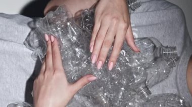 Dikey video. Atık yönetimi. Plastik yeniden kullanım. Ekoloji problemi. Kırık şişeleri olan çevreci kadın gri arka planda ilgi odağı oldu..