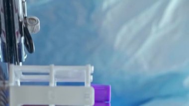 Dikey video. Kan analizi. Laboratuvar araştırması. Tıbbi eldivenli koruyucu ekipman teknisyeni test tüplerini inceleyip panoya sonuçlar yazıyor..