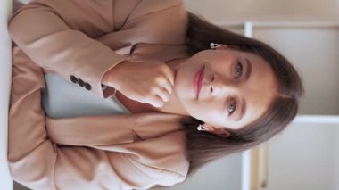 Dikey video. Online terapi. Psikolog aradı. Aktif dinleme. Sakin, gülümseyen bir kadın iş elbisesi içinde el sallıyor..