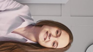 Dikey video. İnternet konuşmacısı. Çevrimiçi koçluk. Gülümseyen çekici kadın kameraya konuşuyor içeriği beğenmek için talimat veriyor..