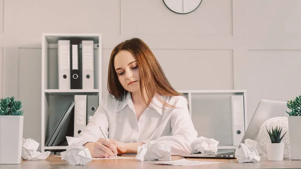 プロジェクトの執筆 オフィスワーク 新しいアイデアを検討する熱心なビジネス女性は 崩壊した紙の中でノートパソコンで座っている — ストック写真