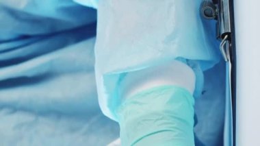 Dikey video. Klinik evrakları. Doktor reçetesi. Uyuşturucu kontrolü. Elleri eldivenli, ilaç şişkinlikleri inceleyen ve panoya notlar yazan bir tıp uzmanı..
