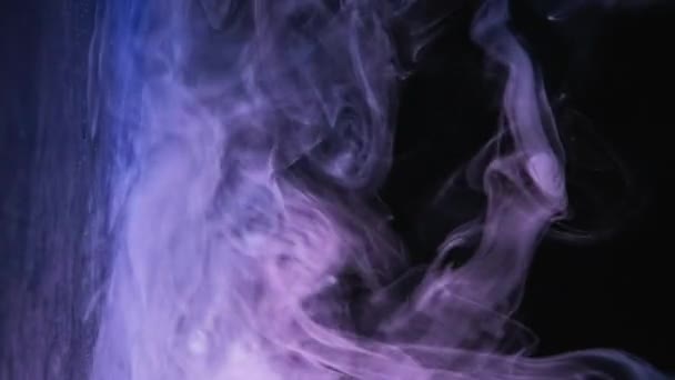 バーティカルビデオ カラーミスト スモークモーション エソテリッククラウド 紫色の青いネオンライトの蒸気は暗黒の自由なスペースの抽象的な背景の光沢のある光沢のある表面の上に流れます — ストック動画