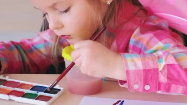 少年艺术家 创意休闲 小女孩在学校的桌子上用水彩画彩虹 并给有才华的孩子画上画笔 — 图库视频影像