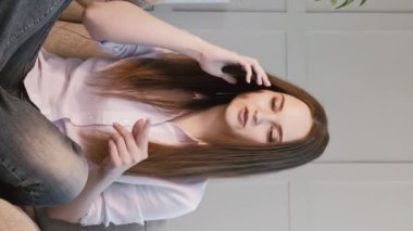 Dikey video. Telefon konuşması. Gezici konuşma. Güzel bir kadın akıllı telefonda konuşuyor evdeki kanepede oturan arkadaşlarıyla iletişim kuruyor..