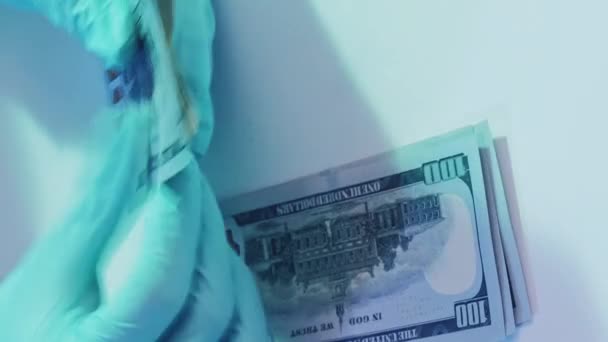 垂直录像 卫生保健工资 药品贿赂 医生们手戴蓝色防护手套 数着白桌上堆着的一百美元钞票 — 图库视频影像
