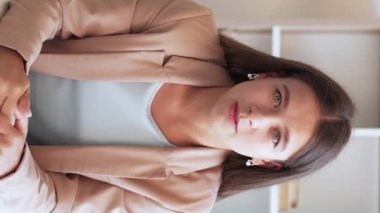 Dikey video. İnternet araması. Online danışmanlık. Uzman blogu. İş elbisesi içinde kendine güveni tam bir kadın iç mekanda el kol hareketi yapıyor..