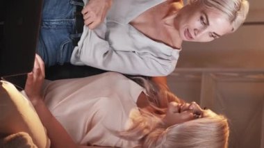 Dikey video. Aile web taraması. İnternetten alışveriş. Anne kız dizüstü bilgisayarla konuşuyor internetten alışveriş yapıyor akşam odasındaki koltukta oturup tartışıyor..