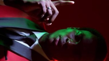 Dikey video. Erkek şüphesi. Bir sorum var. Yeşil, neon ışıklı, düşünceli, kafası karışmış, smokin giymiş, koyu renk düşünen, güvenilmez bir beyefendi..