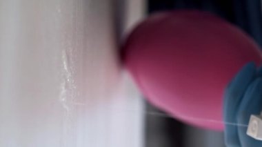 Dikey video. Temizlik servisi. Profesyonel ev hanımı. Temizlikçi koruyucu eldivenler takıp deterjan sıkarak masa yüzeyini mikrofiber silecekle temizliyor..