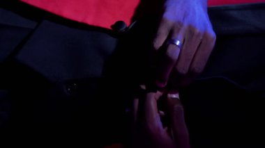 Dikey video. Centilmen tarzı. Şık bir moda. Lüks parti görünüşü. Neon ışığı tanınmayan adam koyu mor üzerine kırmızı şık smokin ilikliyor..