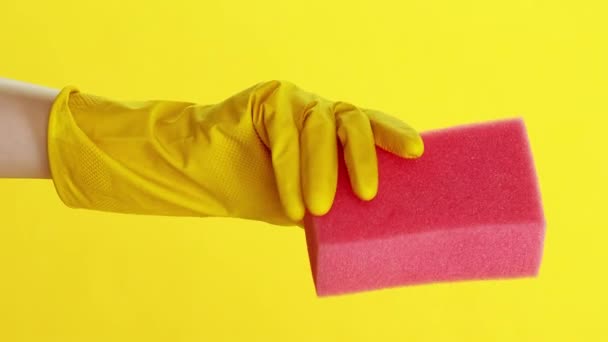 バーティカルビデオ プロの家庭 ワイピングツール ジャニスター装備 黄色の背景に隔離されたピンクのスポンジが付いている保護手袋の手 — ストック動画