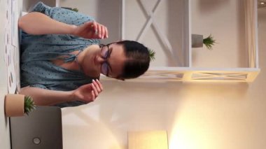 Dikey video. İş yorgunluğu. Göz yorgunluğu. İşkolik sorunu. Migren ağrısından muzdarip yorgun bir kadın modern ofis işyerinde kafasına dokunuyor..
