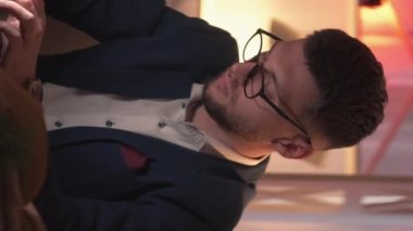 Dikey video. İş araştırması, meşgul adam. Çevrimiçi iletişim. Bilgisayarı daktilo eden zeki bir adam karanlık odanın içinde oturuyor..