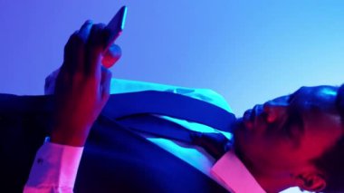 Dikey video. Sinir bozucu bir sohbet. Çevrimiçi çatışma. Mobil anlaşmazlık. Kırmızı mavi ışık çılgın rahatsız iş adamı telefonda kızgın mesaj atıyor..