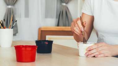 Boya çizimi. Sanatsal ekipman. Tanımlanamayan kadın ressam elleri renkleri karıştırarak stüdyodaki masada fırçalayabilir..