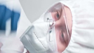 Dikey video. Sağlık virologu. Hastane evrakları. Beyaz elbiseli kadın doktor. Gri arkaplandaki notlarla işaret ediyor..