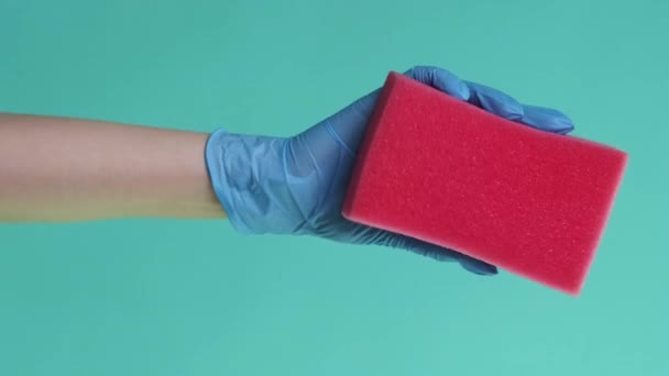 バーティカルビデオ ティディ クリーニング 洗濯ツール 表面衛生について 緑の背景に隔離されたピンクのスポンジを絞るゴム製手袋のジャニスター手 — ストック動画