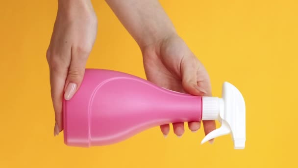 バーティカルビデオ クリーニングツール 洗剤製品について 衛生設備について 黄色の背景に隔離されたピンクの化学衛生スプレー ボトルが付いている女性の手 — ストック動画