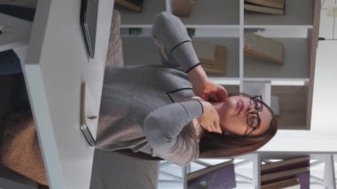 Dikey video. İşini bitir. Yorgun bir kadın. Isınma egzersizleri. Yorgun bir kadın dizüstü bilgisayarı kapatırken gergin hissediyor..