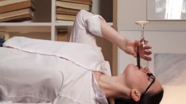 Dikey video. Alkol partisi. Ev eğlencesi. Pozitif yaşam tarzı. Tasasız bir hafta sonu. Neşeli kadın kadehle dans edip yalnız başına şarap içiyor..